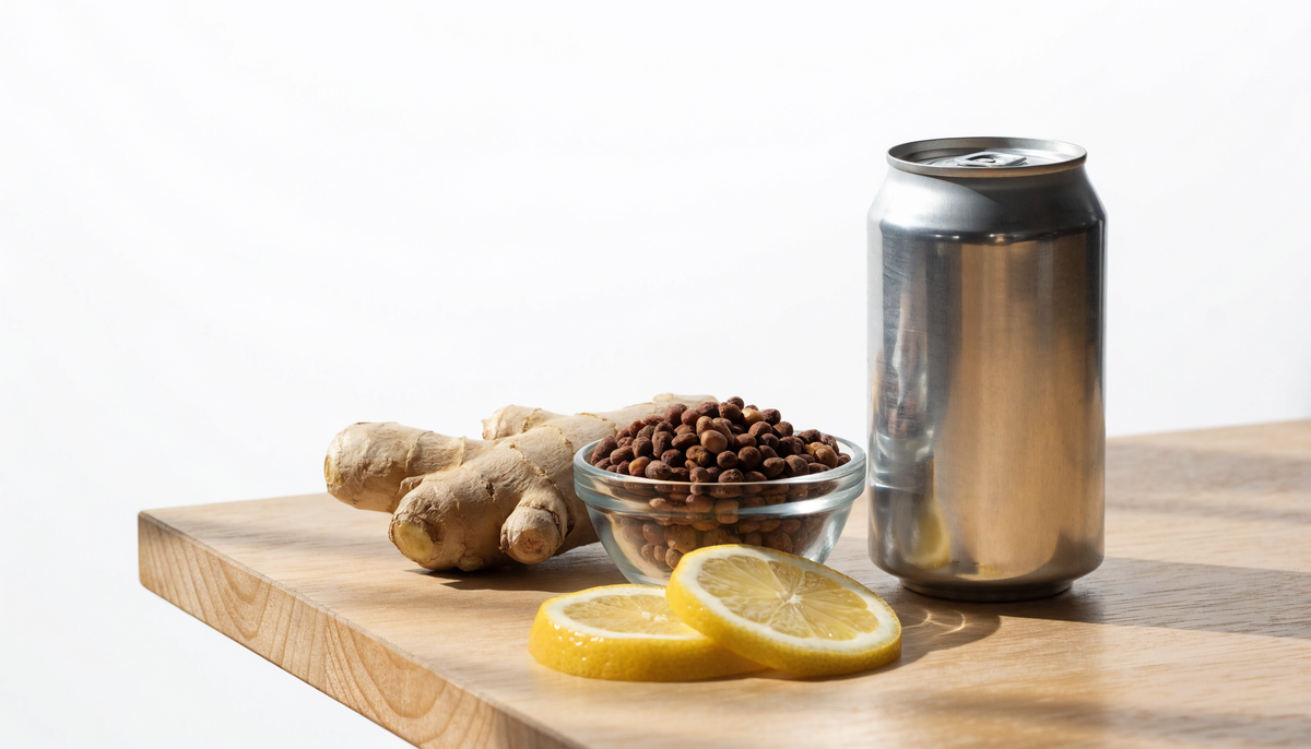 Canette sans marque, graines de guarana, gingembre et citron sur une table en bois clair