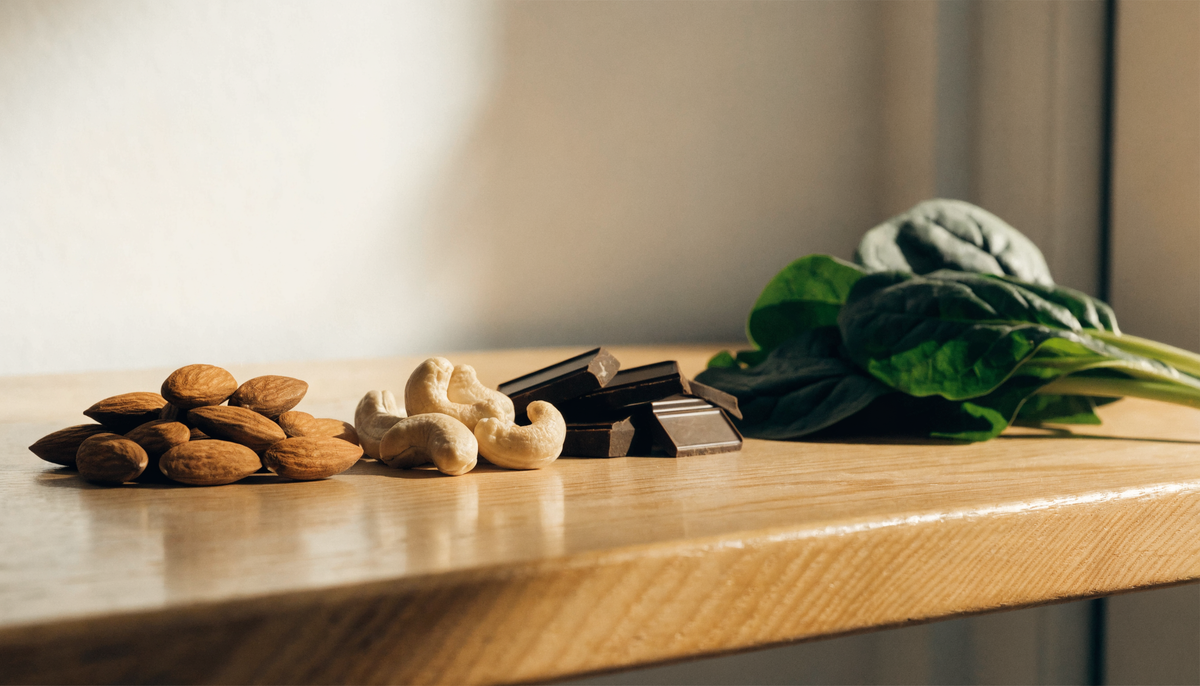 Aliments riches en magnésium, amandes, noix de cajou et chocolat noir sur une table en bois