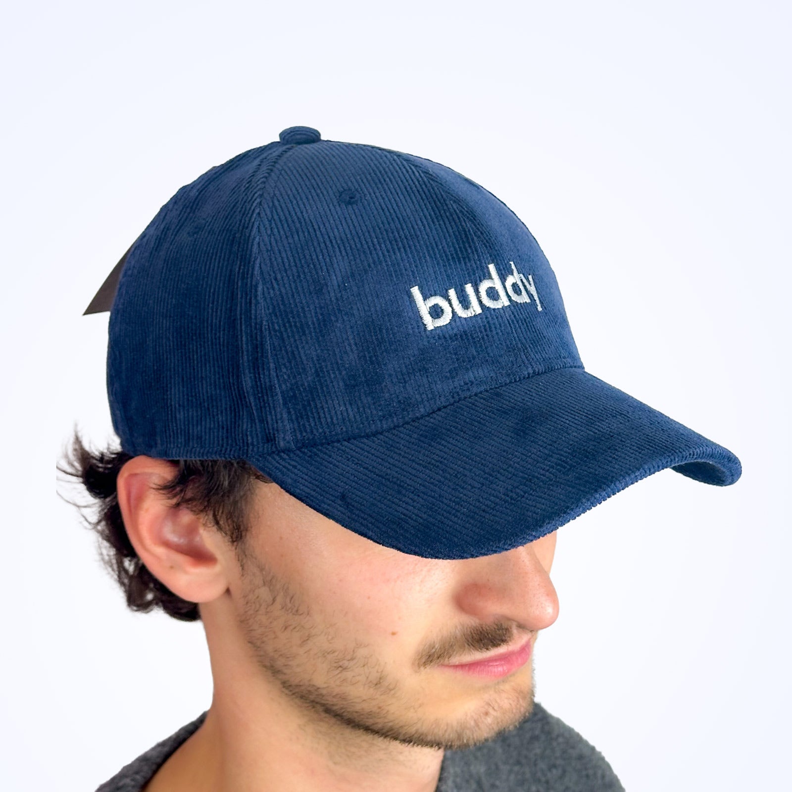 Casquette bleu marine Buddy en velours côtelé avec logo brodé blanc, portée par un modèle masculin